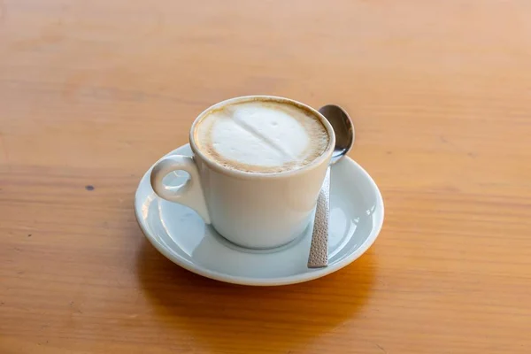 木製のテーブルのスプーンの横にソーサーにコーヒーカップのクローズアップ — ストック写真