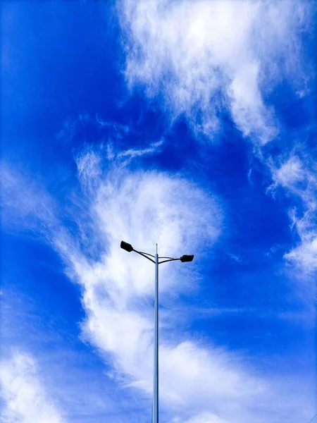 Pionowe Ujęcie Słupa Oświetleniowego Tle Niebieskiego Zachmurzonego Nieba — Zdjęcie stockowe
