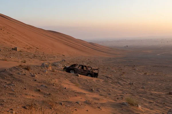 砂漠の澄んだ空の下の砂の山の斜面の放棄された車 — ストック写真