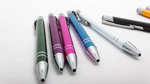 白桌子上一排不同颜色的钢笔的特写镜头 — 图库照片