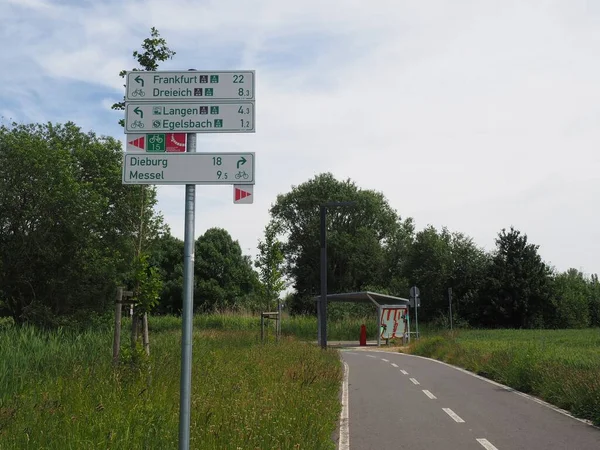 A park with sign posts at cycle track surrounded by meadows and trees in Egelsbach, Germany