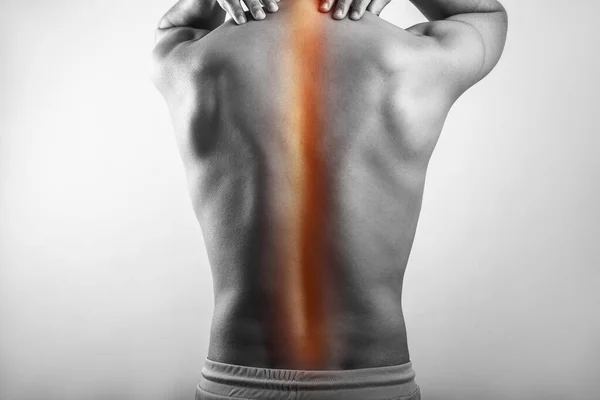 Shirtless black and white muscular man suffering from spinal cord injury, backache highlighted in glowing red.
