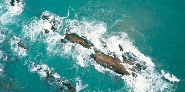 从空中俯瞰大海中的泡沫波涛和岩石 — 图库照片