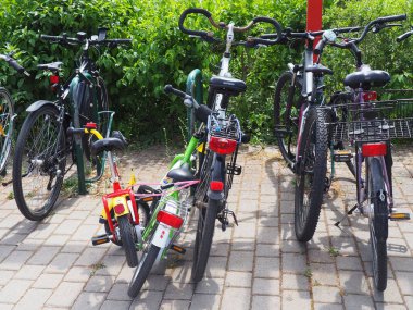 Egelsbach, Almanya 'daki bir parkta çalıların önüne park edilmiş kilitli aile bisikletlerinin yakın çekimi.