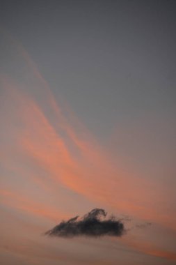 Gökyüzünde turuncu çizgili gri bir bulutun dikey görüntüsü.