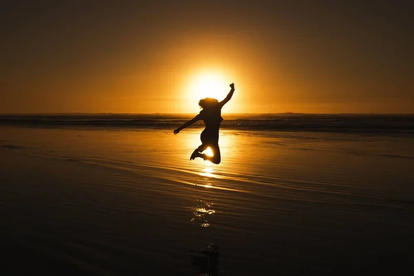 Een Silhouet Van Een Jong Meisje Springend Een Strand Bij — Stockfoto