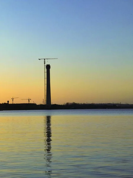 Una Silueta Una Torre Una Grúa Cerca Lago Atardecer —  Fotos de Stock