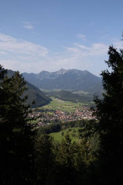 Gün ışığında küçük bir köyü çevreleyen güzel bir dağ manzarasının dikey görüntüsü.