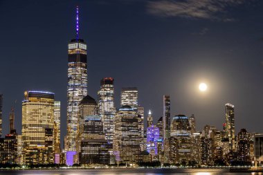 Geceleri gökyüzünde dolunay olan New York City binalarının manzarası.