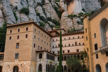 Montserrat, İspanya 'da kayalık bir dağın önündeki manastır binalarının yatay görüntüsü