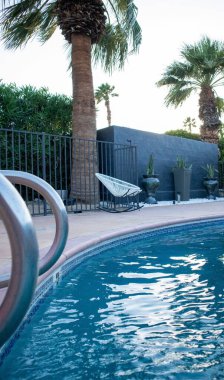 Havuz kenarındaki beyaz kabuklu koltuğun dikey görüntüsü.