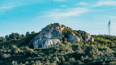 Çimlerle çevrili bir tepede büyük bir kaya.