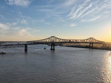 Mississippi nehrinin üzerindeki bulutlu gökyüzü arka planında gün batımında metal bir köprünün hava görüntüsü.
