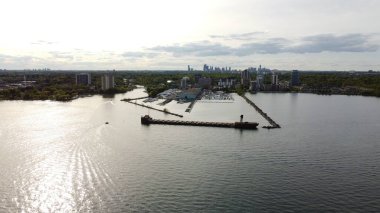 Sakin bir denizde uzun bir geminin güzel bir hava manzarası ve günbatımında arka planda şehir.