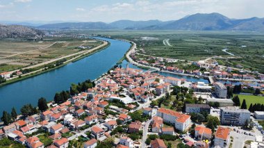 Yeşil tarlalar ve dağlarla çevrili şehir ve nehrin hava manzarası..