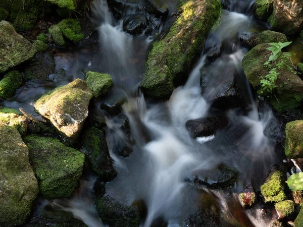 岩の形成を流れる小さな川の長い露出ショットでは 日光が入ってくる — ストック写真