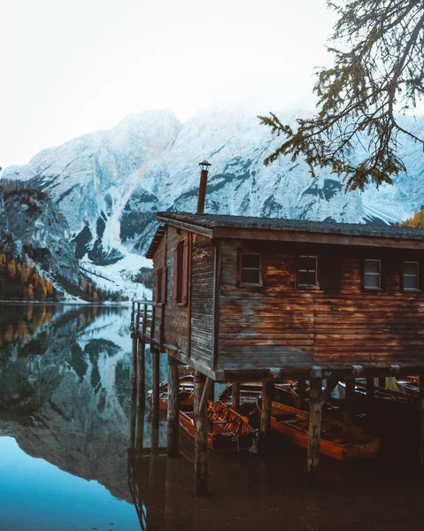 Eine Vertikale Aufnahme Eines Holzhauses See Mit Schneebedeckten Bergen Hintergrund — Stockfoto