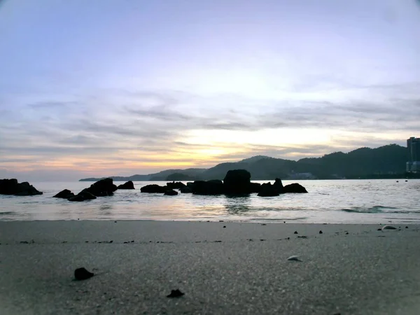 夕日の後 海に岩がある滑らかな砂浜の美しいショット — ストック写真