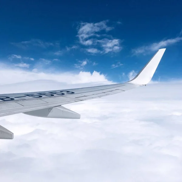 白い雲と青い空に向かって窓から捉えられた飛行機の翼 — ストック写真