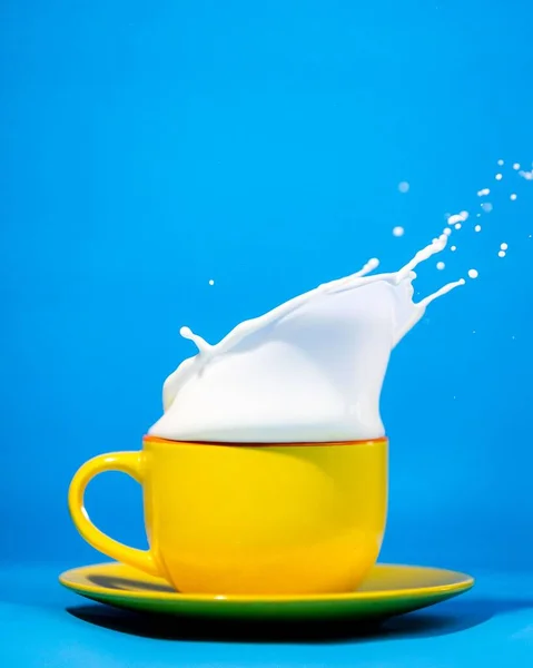 Vertikal Bild Gul Mugg Med Stänk Mjölk Blå Bakgrund — Stockfoto