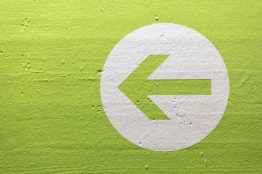 Yeşil bir duvarda izole edilmiş beyaz bir dairedeki bir ok yönü gösteriyor.