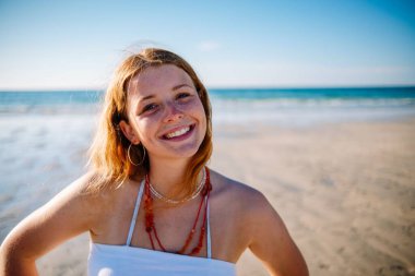 Kumsalda gülümseyen sevimli sarışın bir İngiliz kadın.