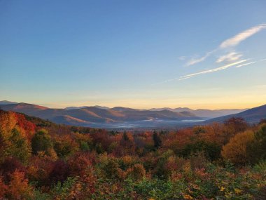 Sonbaharda gün batımında gökyüzü arka planında rengarenk doğayla güzel bir dağ manzarası.