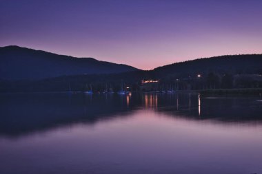 Gmund am Tegernsee, Bavyera, Almanya 'da dağların yansıması ve su yüzeyinde ışık bulunan göl.