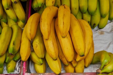 Hanging bananas placed on a shelf for sale within a market