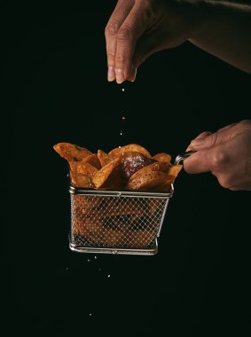 Siyah arka planda izole edilmiş sepetteki kızarmış patatesler.