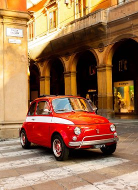 İtalya 'nın Bologna şehrinde yol kenarına park edilmiş klasik İtalyan arabası. Fiat 500. Beyaz bukleli kırmızı.