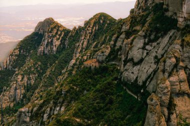 Sisli bir arka planı olan kayalık bir yamaçtaki izole bir evin yatay görüntüsü.
