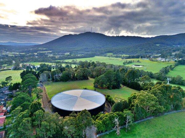 Aerial shot of a green field and Mount Dandenong in Victoria Australia
