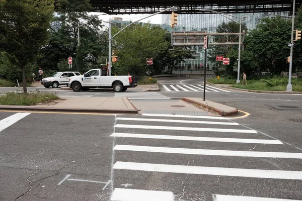 New York 'ta bir caddede bir yaya geçidi. Gündüz vakti bitki örtüsü ve park edilmiş arabalarla.