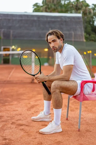 금발에 머리의 남자가 더러운 코트에서 테니스 라켓을 의자에 — 스톡 사진