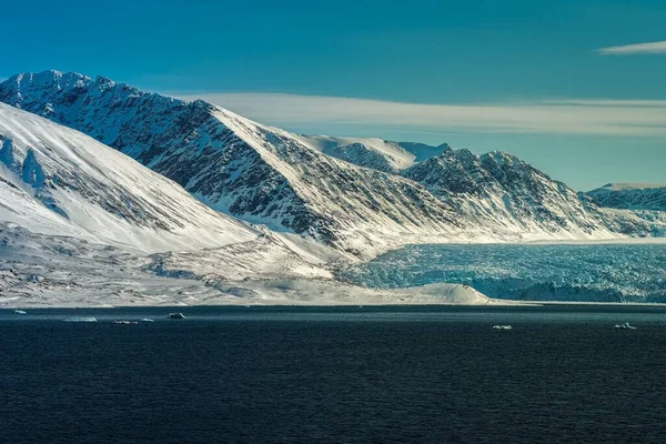 北极山脉的全景 在浅蓝色天空的冰川旁边有暴露的岩石 — 图库照片
