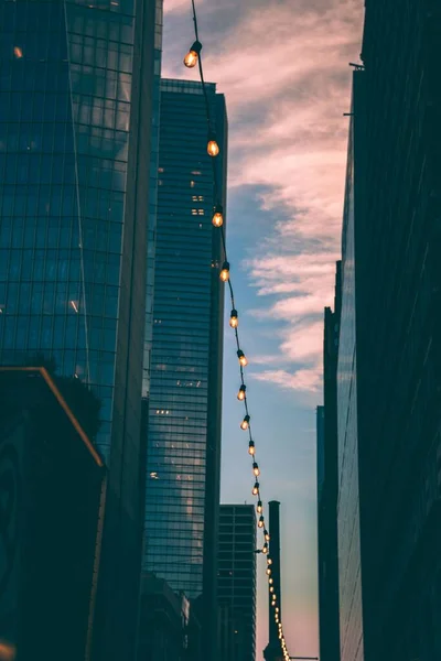 Ângulo Vertical Baixo Luzes Penduradas Entre Edifícios Modernos Durante Pôr — Fotografia de Stock