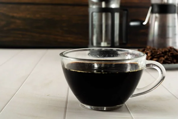 背景に要素を入れた透明なガラスカップの上のブラックコーヒー — ストック写真