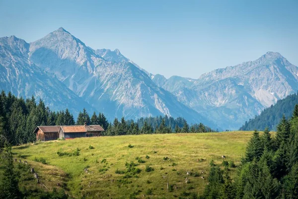 Tagsüber Eine Wiese Mit Bauernhäusern Und Hohen Bergen Hintergrund — Stockfoto