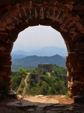Taş bir kemer binasından görünen bir tepenin üstünde bir harabe.