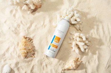 Beyaz kum ve deniz kabuğunda güneş kremi.