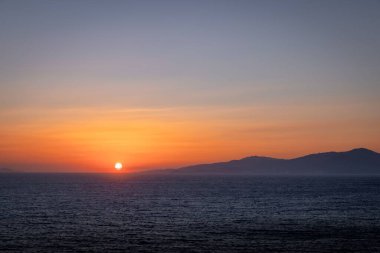 Gün batımında tepelerin ardında güzel bir deniz manzarası