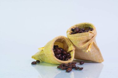 Çuval dolusu kavrulmuş kahve çekirdekleri beyaz arka planda, makro fotoğraf.