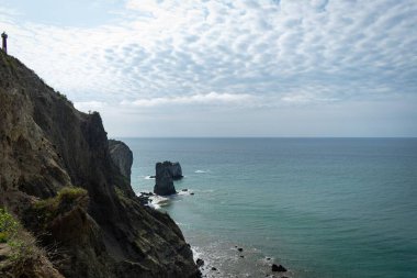 Kayalıkların manzarası ve bulutlu gökyüzü ile mavi deniz.