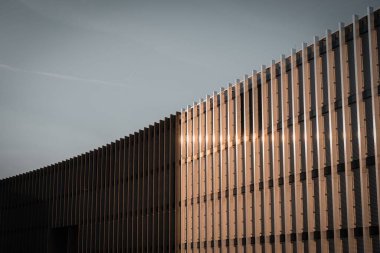 Gri gökyüzünün altındaki modern bir binanın dış tasarımı.