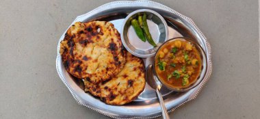 Baharatlı civciv köri veya Chola Masala veya Chana Masala veya Chole Kulche veya Cholay dilimlenmiş soğan, yeşil kişniş yaprağı ve tereyağıyla süslenmiş.