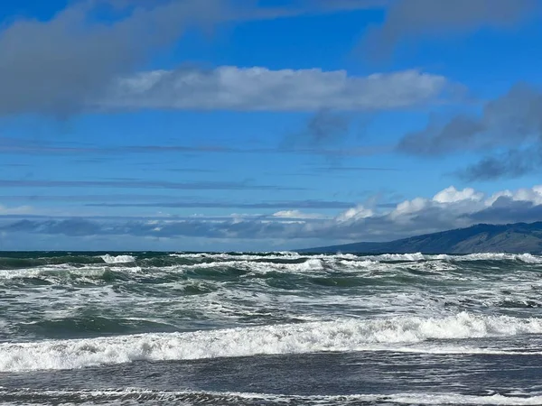 青い空の下で波が飛び散るビーチの美しいショット — ストック写真