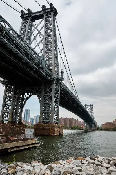 水景と灰色の雲とニューヨーク市のブルックリン橋の垂直ショット — ストック写真
