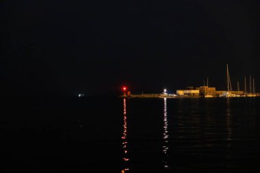 Trieste körfezinde yansıyan deniz fenerinin manzarası, gece vakti İtalya