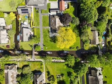 Nehirde yeşil ağaçları, evleri ve tekneleri olan Giethoorn köyünün havadan görünüşü.